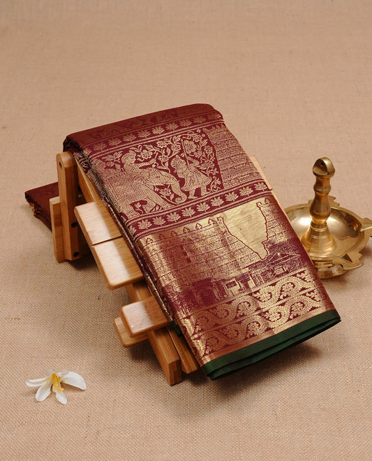 Dark Maroon colour Kanchipuram Samudrika Pattu saree featuring an exclusive gold zari weave of the historic Padmanabhaswamy Temple East Gopuram on the border and pallu, with Anantha Sayanam motif, paired with self colour blouse piece.