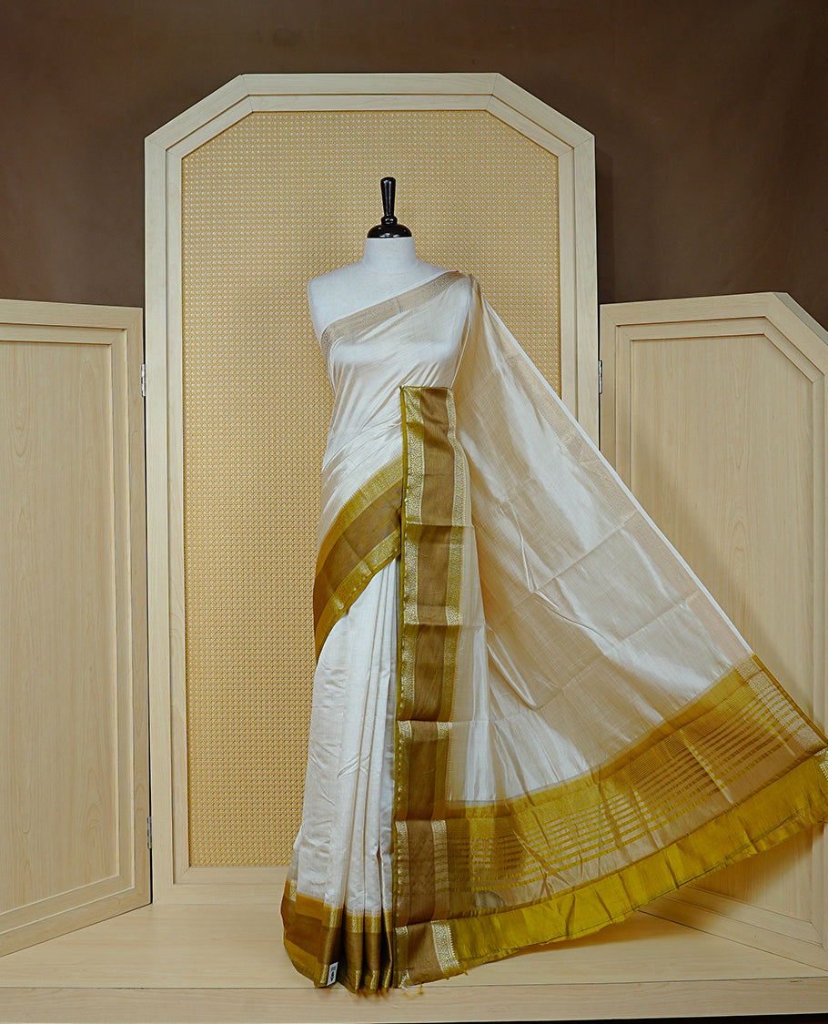 Cream colour semi Tussar silk saree featuring  Elegant body, Complemented by contrast Olive with rich zari detailed for onam special, paired with contrast Blouse for Festive look.