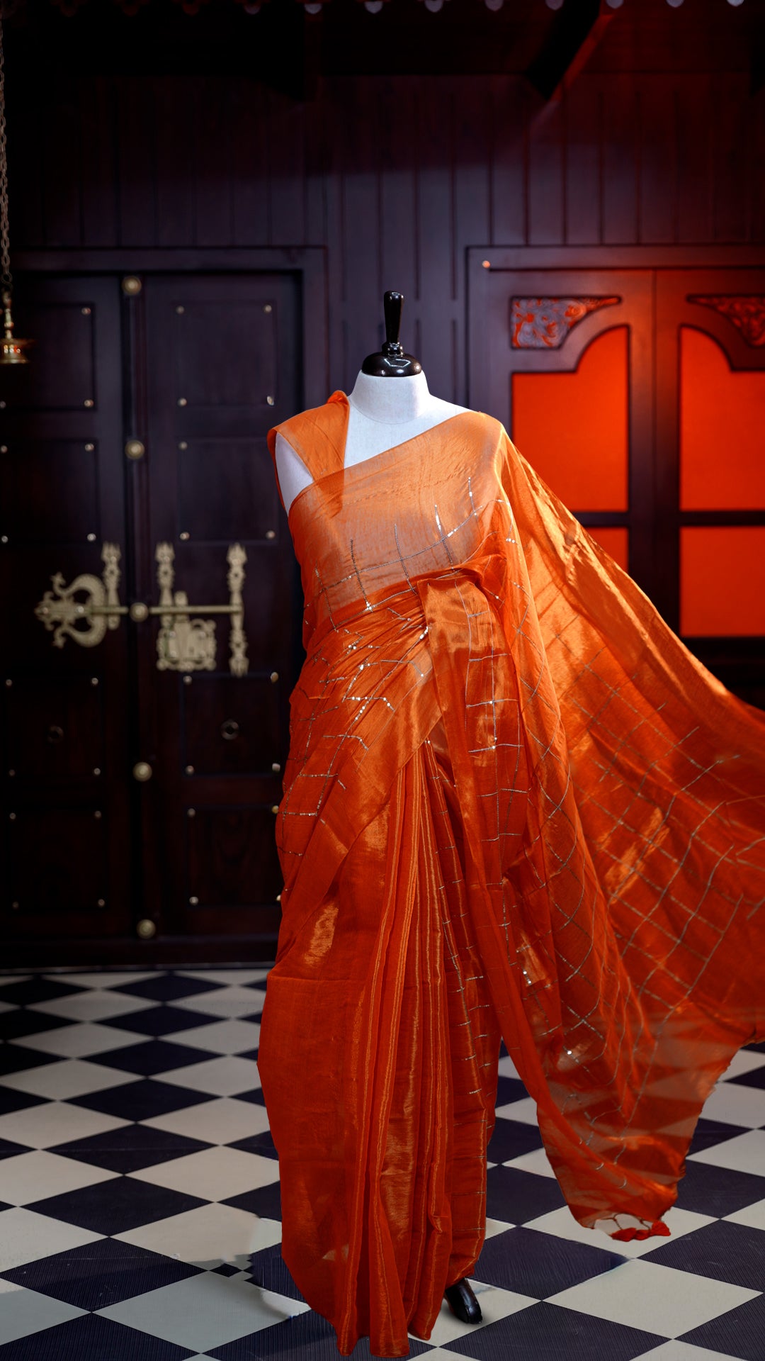 Orange colour Semi Tissue Material saree with on all-over check design with silver sequin work on body, comes with a self blouse and a self pallu.