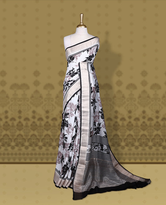 White colour saree with black and mauve floral prints, featuring a contrast zari border and detailed pallu & Comes with a matching blouse piece.