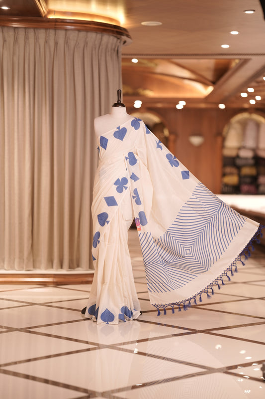 Off white colour kerala cotton saree adorned with blue colour card suit motifs , The pallu features striking zigzag patterns with tassel detailing, creating a perfect fusion of tradition and modern sophistication.