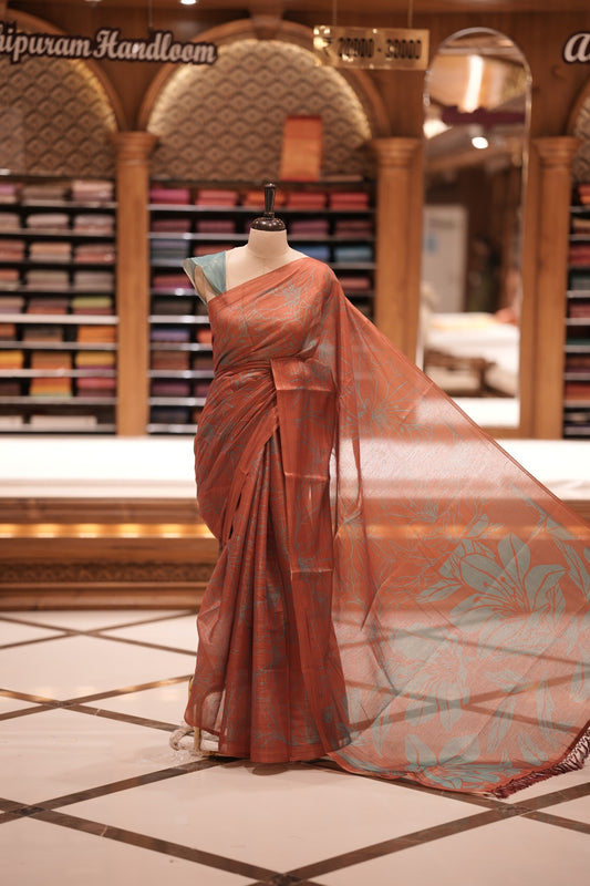 Brick Red & Teal blue colour Semi linen tissue saree featuring full digital floral prints across the body, The saree is highlighted with a contrast floral printed pallu and comes with a plain contrasting blouse piece.