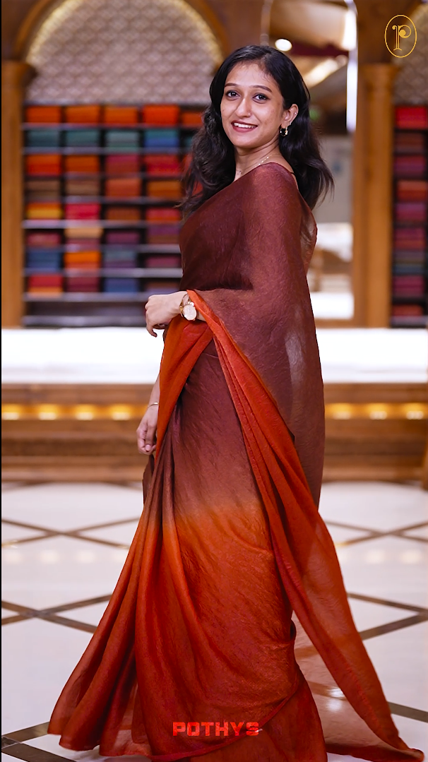 Brown orange colour saree with a soft textured body in deep orange, a rich pallu blending brown hues, and a subtle, seamless border for a graceful and contemporary drape & Comes with a matching blouse.