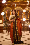 Burnt Orange colour Kancheepuram Silk saree with Golg Zari design, Black Colour Traditional border and pallu, paired with matching blouse piece.
