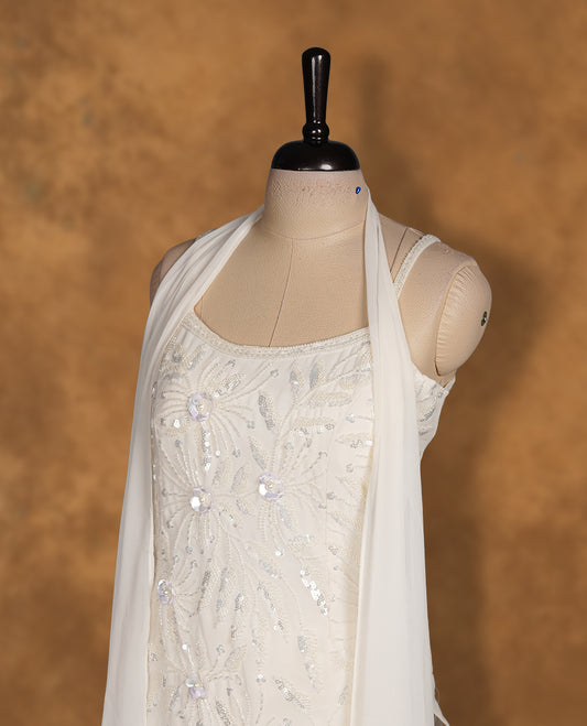 Ivory white colour sharara set featuring delicate sequin and thread floral embroidery across the body, a soft scoop neckline, and a flowy sharara silhouette, paired with a sheer matching dupatta.