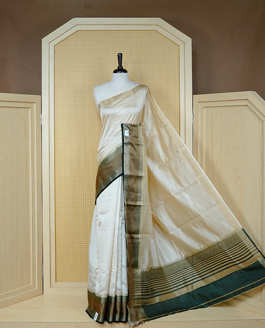 Cream colour semi Tussar silk saree featuring  Elegant body, Complemented by contrast Bottle Green with rich zari detailed for onam special, paired with contrast Blouse for Festive look.