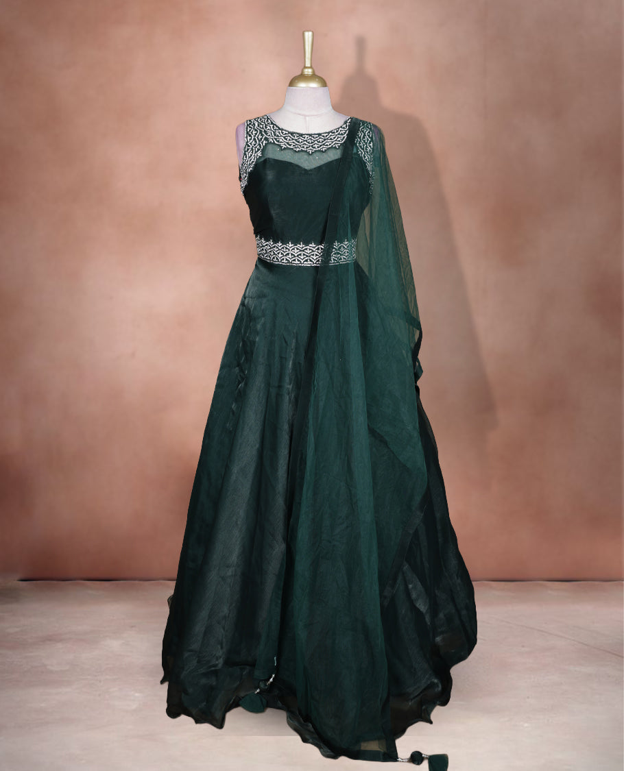 Emerald green colour Gown with stitched sleeveless blouse featuring embellished neckline and waist detailing, paired with a matching stitched flared lehenga and sheer dupatta.