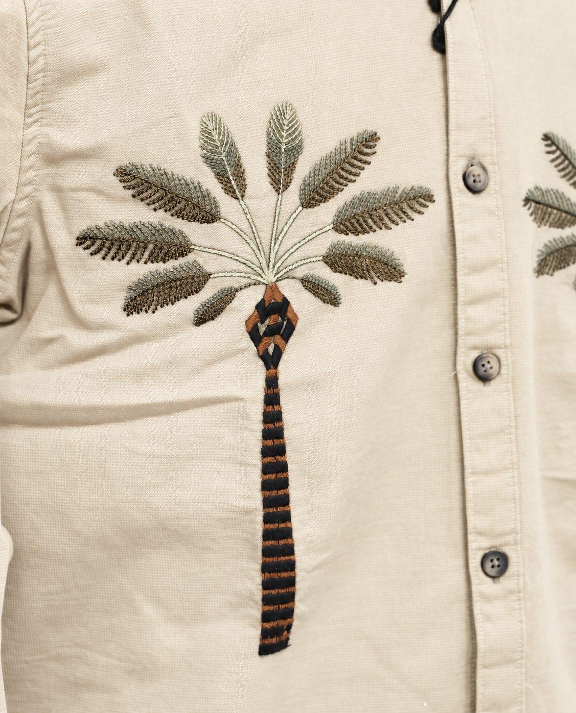 Cream colour full sleeve shirt with a tree embroidery pattern on the body.