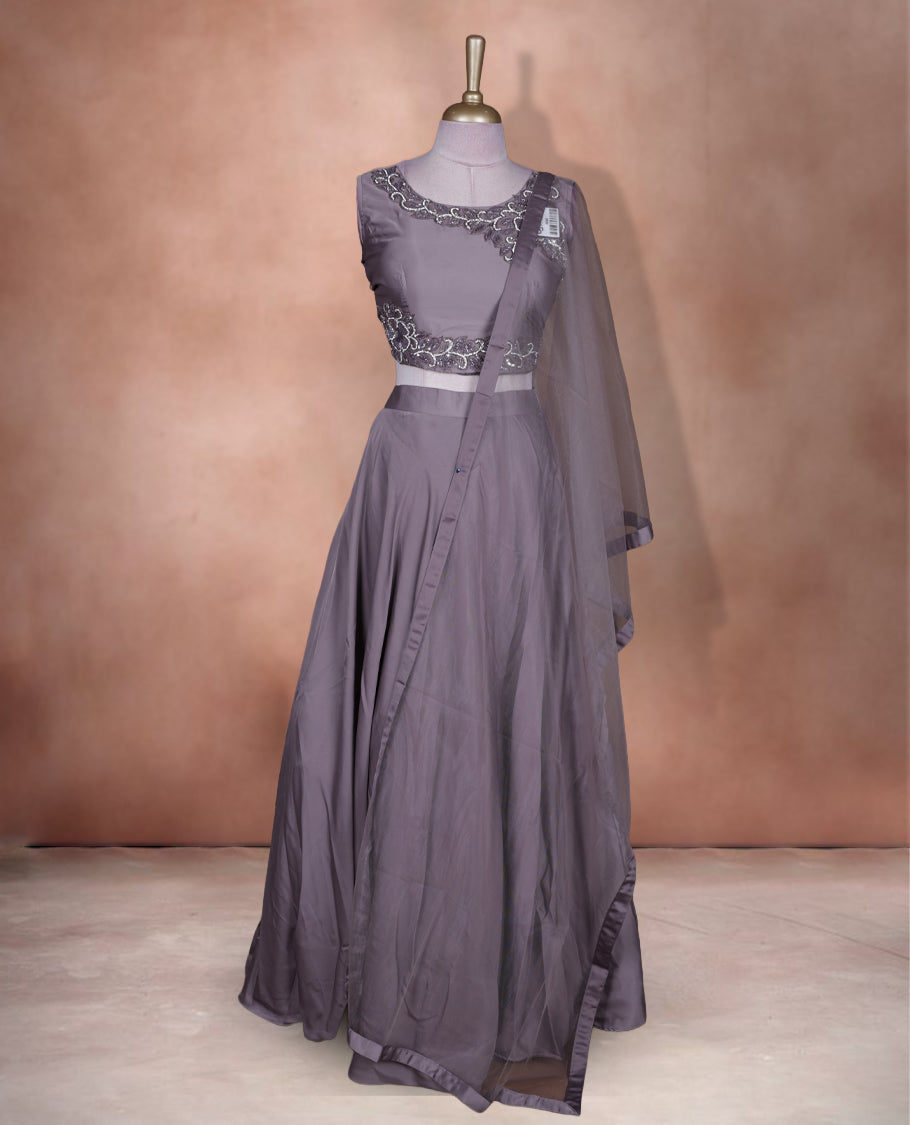 Dusty lavender colour lehenga set with stitched sleeveless blouse featuring intricate bead and sequin embroidery along the neckline and waist, paired with a matching stitched flared lehenga and plain sheer dupatta.