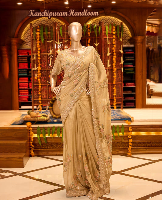 Dusty Gold colour tissue organza designer saree featuring delicate Floral embroidery and beadwork across the body, finished with heavy embellished border and pallu, paired with a matching tissue organza designer readymade blouse.