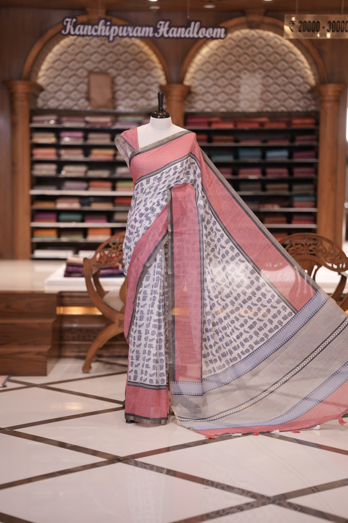 White colour soft linen saree adorned with cute elephant prints all over the body, complemented by a contrast woven border and paired with a matching printed blouse piece