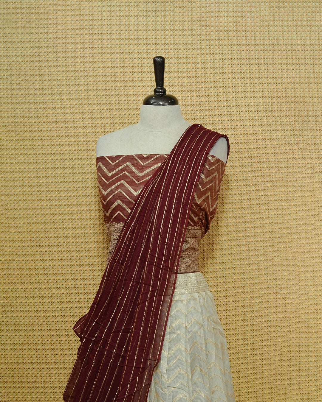 Cream colour Semi Stitched Dhavani set Featuring Gold zari Zigzag pattern With Traditional border skirt, Contrast Maroon colour Dupatta, Matching blouse piece.