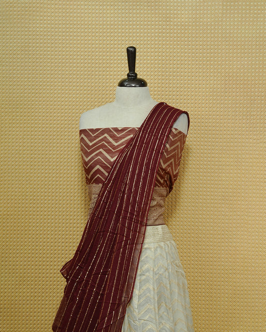Cream colour Semi Stitched Dhavani set Featuring Gold zari Zigzag pattern With Traditional border skirt, Contrast Maroon colour Dupatta, Matching blouse piece.