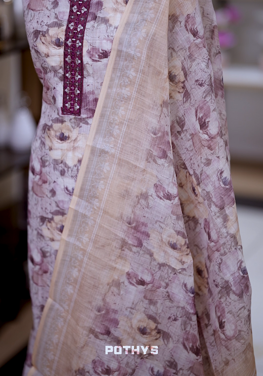 Off white colour jute cotton salwar material with grape colour leaf prints, featuring embroidery and mirror work on the neckline, paired with a printed dupatta and a contrast grape colour bottom for a graceful and elegant look.