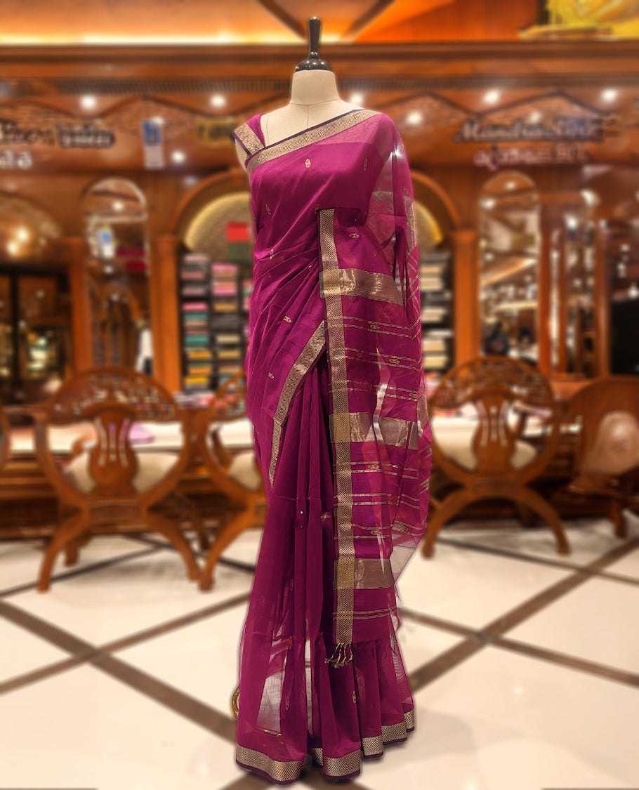 Dark reddish brown colour Maheshwari silk Cotton saree with a plain body, complemented by a geometric designed gold border and a traditional pallu, with a matching blouse.