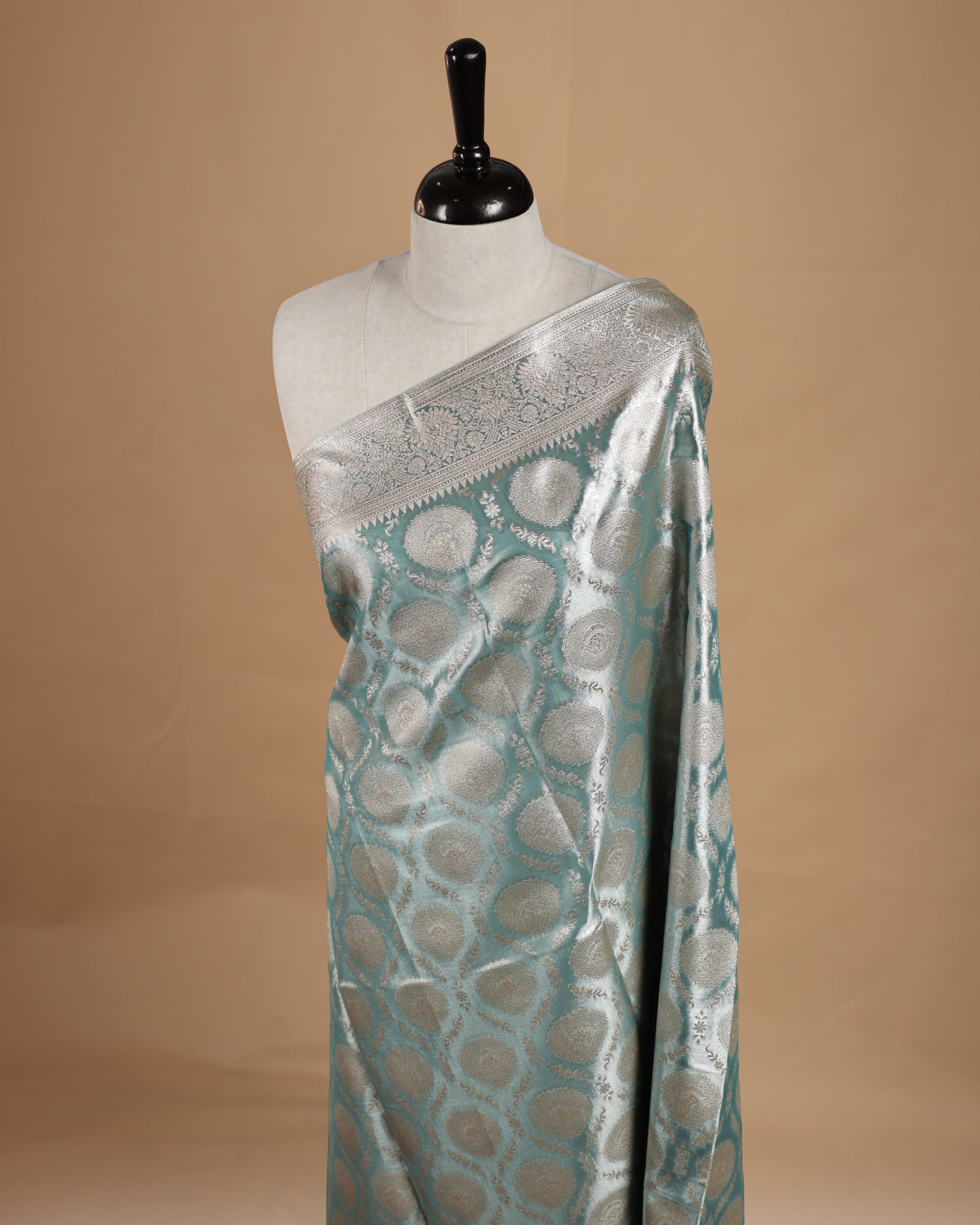 Pastel Blue colour semi tissue silk saree featuring floral zari motifs on body, complemented by gold zari traditional border, paired with matching blouse piece.