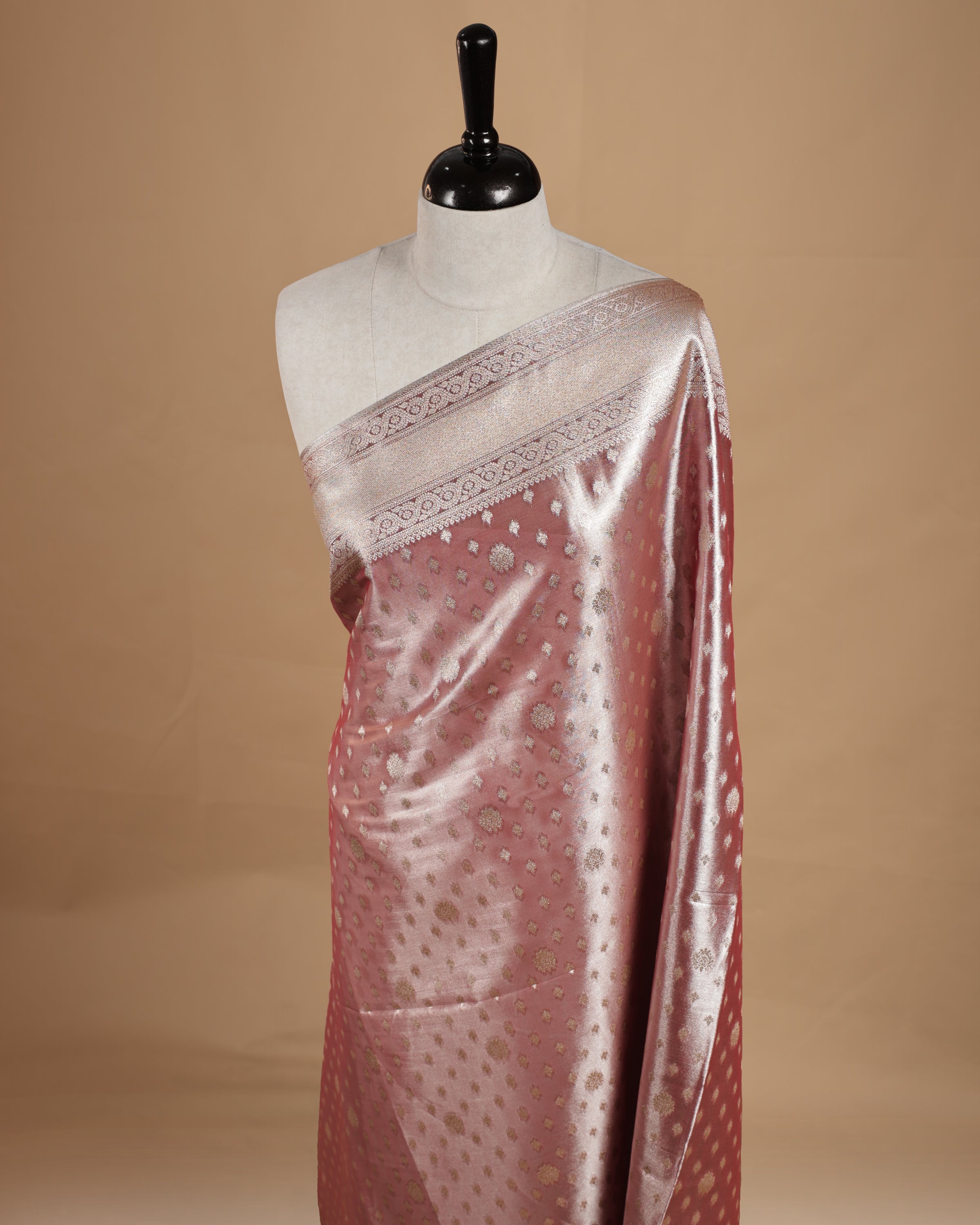 Pastel peach colour semi tissue silk saree featuring floral zari motifs on body, complemented by gold zari traditional border, paired with matching blouse piece.