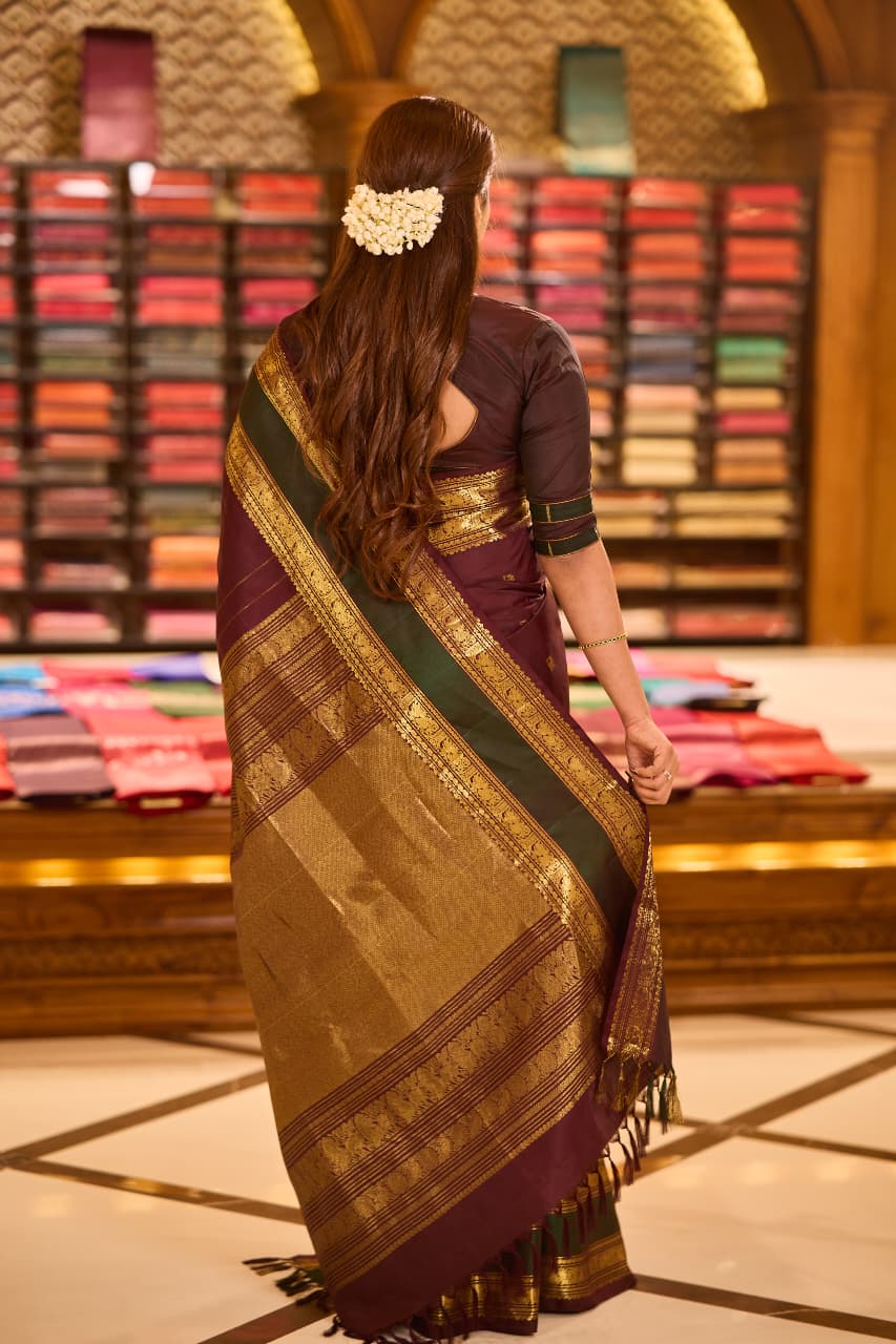 Dark maroon colour pure Kancheepuram saree with gold zari Banarasi paisley peacock motifs on the body traditional green border with peacock pattern grand pallu with floral  motifs paired with matching blouse.