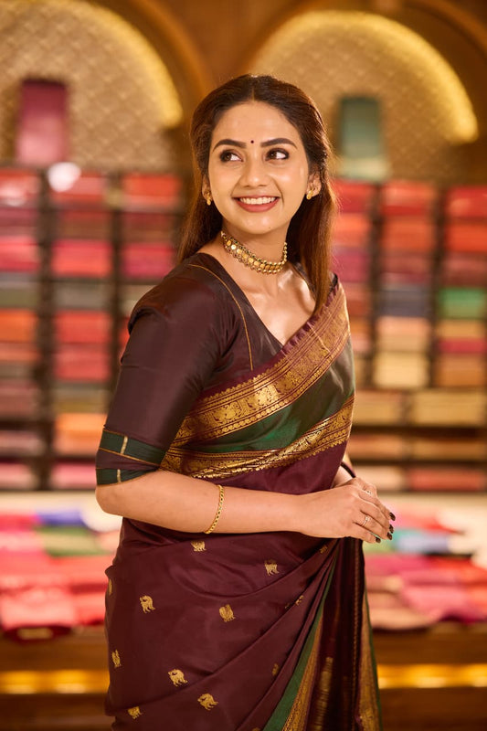Dark maroon colour pure Kancheepuram saree with gold zari Banarasi paisley peacock motifs on the body traditional green border with peacock pattern grand pallu with floral  motifs paired with matching blouse.
