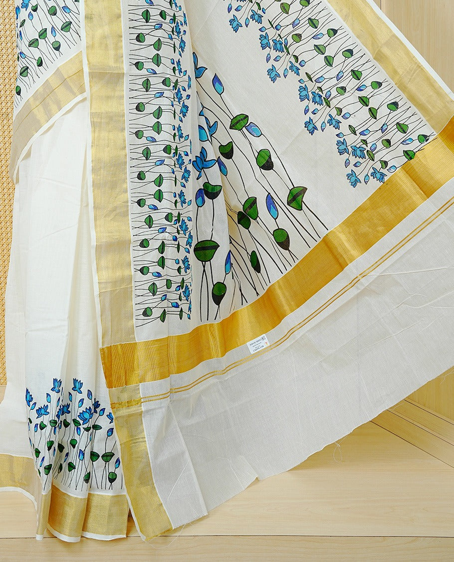 Cream Colour Cotton Kerala Saree Featuring Delicate Blue Floral Print Across The Body, Enhanced With A Gold Zari Border And A Rich Gold Zari Pallu, Finished With A Matching Blouse Piece
