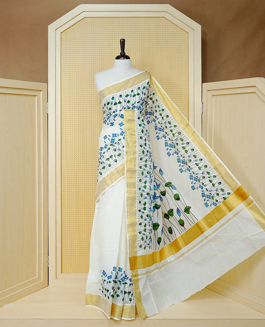 Cream Colour Cotton Kerala Saree Featuring Delicate Blue Floral Print Across The Body, Enhanced With A Gold Zari Border And A Rich Gold Zari Pallu, Finished With A Matching Blouse Piece