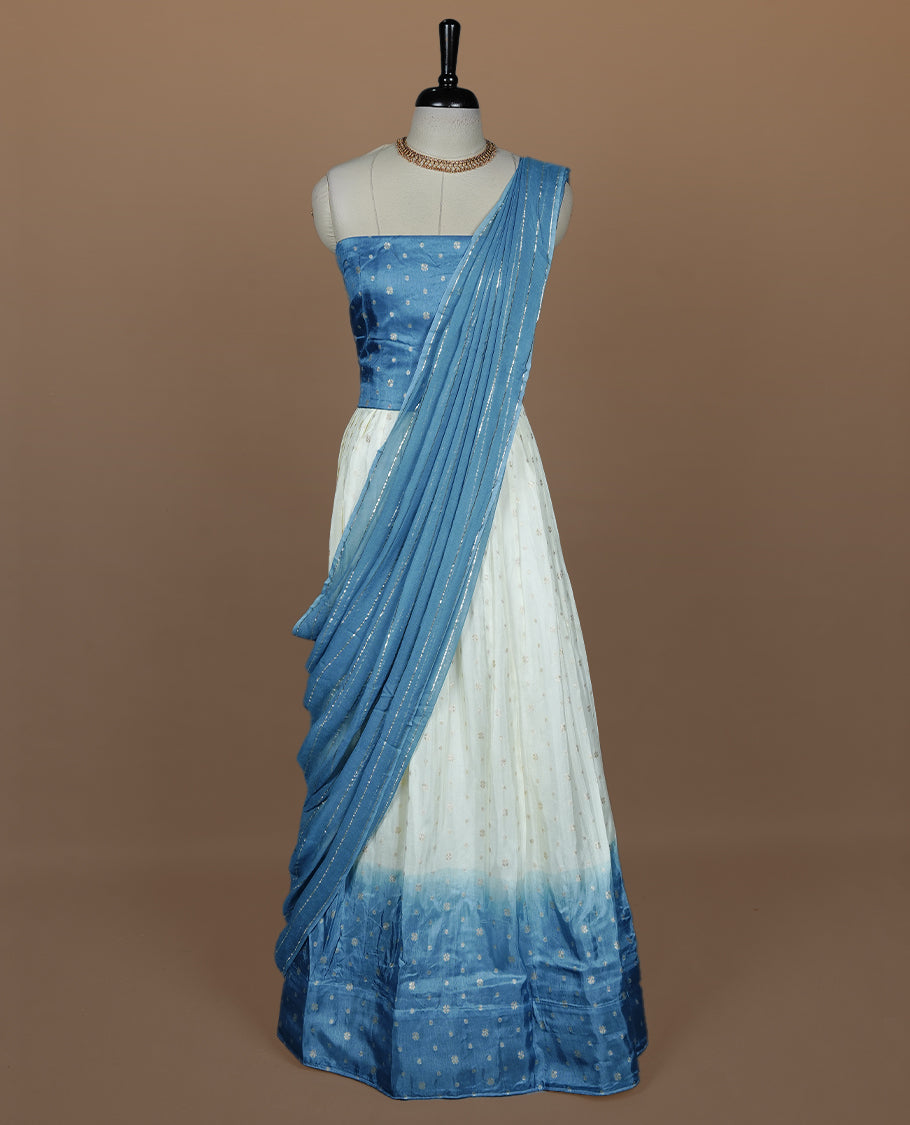 Off white semi banaras semi stitched dhavani set featuring gold zari motifs and contrast Bluecolour border, unstitched gold zari blouse piece and matching Duptta with gold zari stripes.