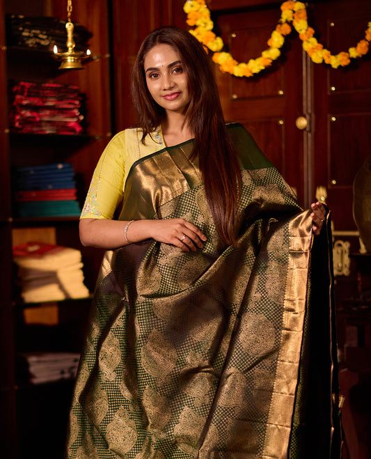 Deep green pure Kancheepuram silk saree featuring elegant gold zari Motifs, a rich gold zari pallu, and a broad gold zari border, paired with a matching blouse.