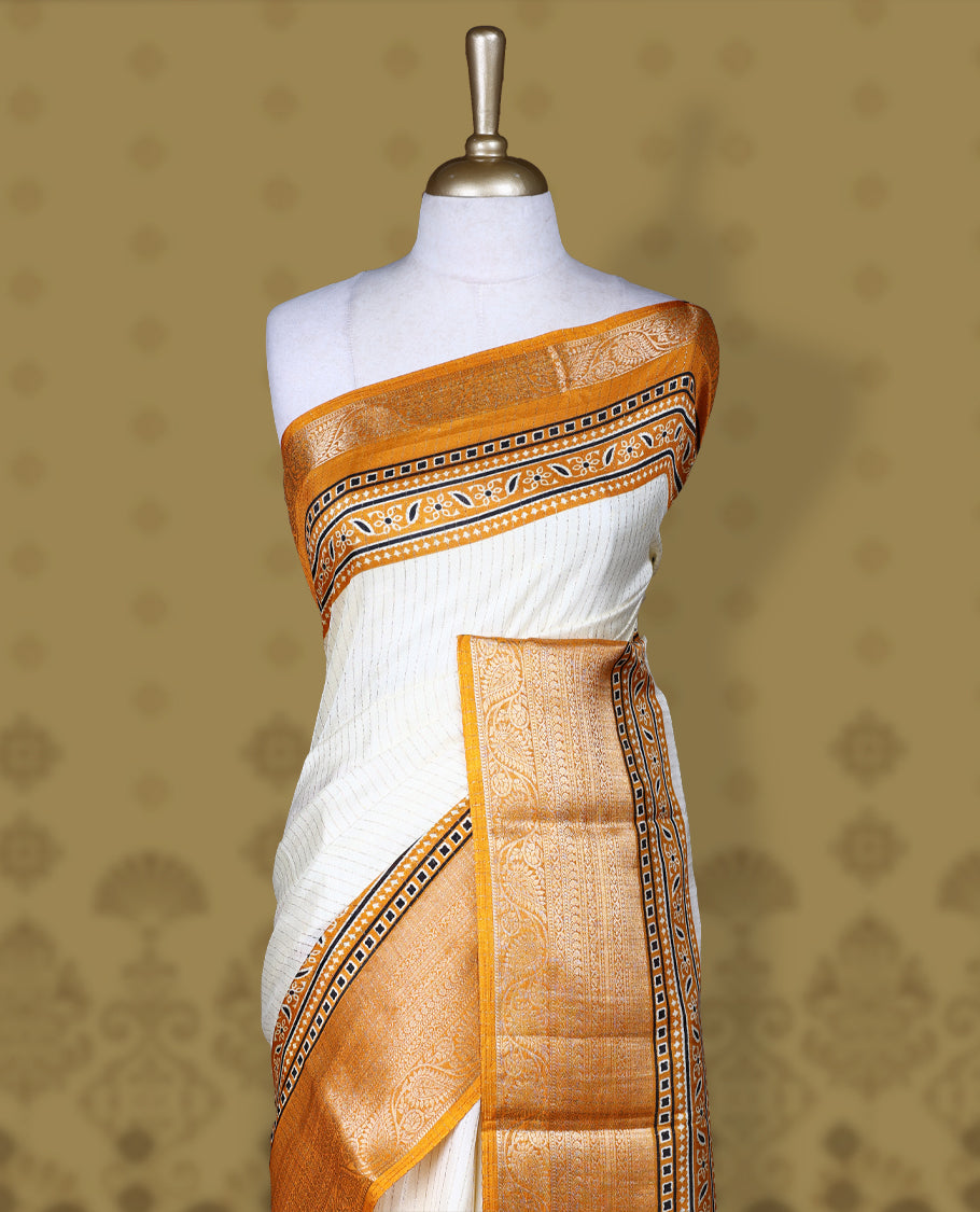 Beige Dolla silk saree featuring antique zari stripes across the body, adorned with a striking Ajrak and Traditional yellow colour border, ajrak printed pallu and paired with a perfectly matching blouse.