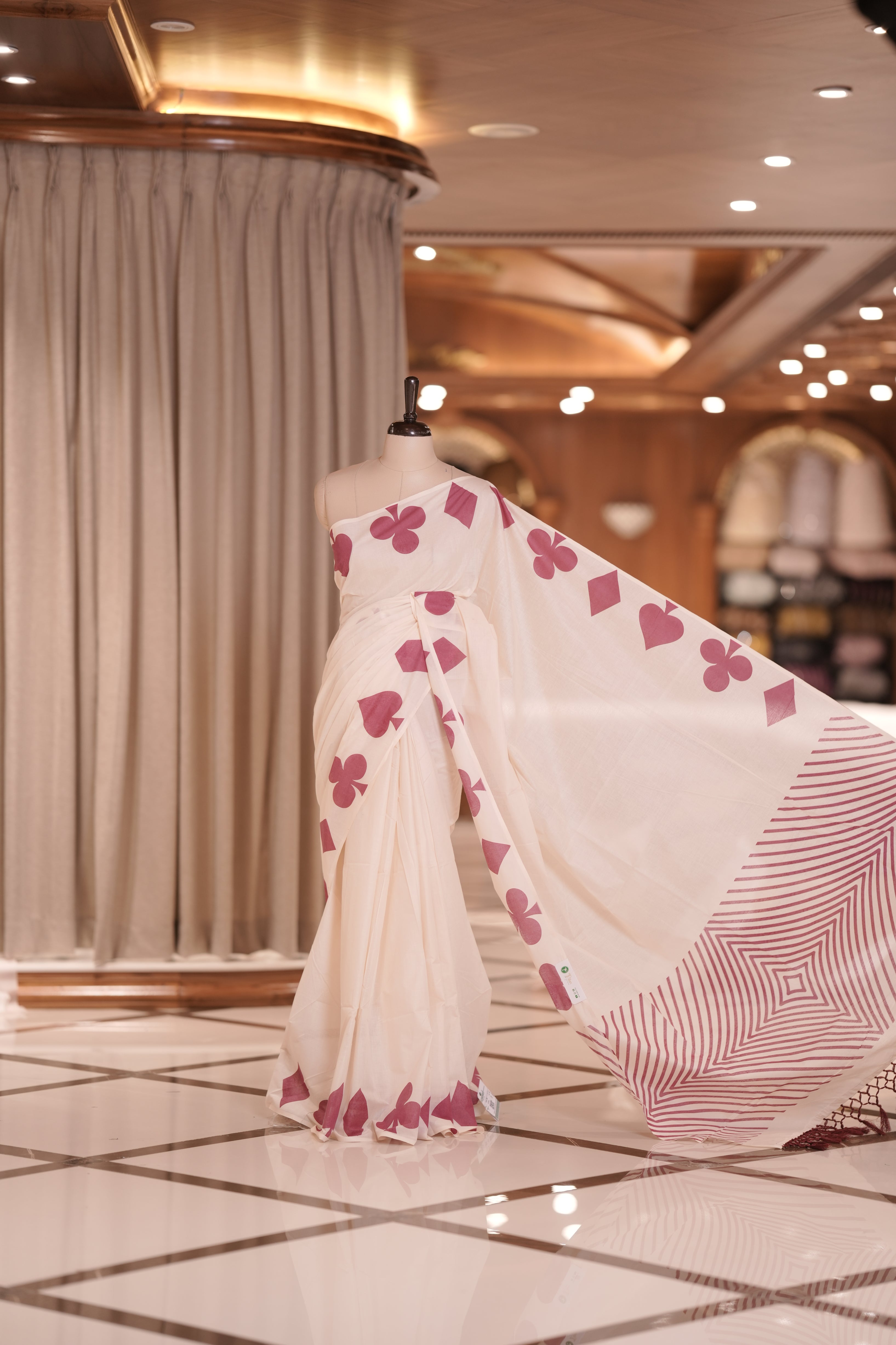 Off white colour kerala cotton saree adorned with pink colour card suit motifs , The pallu features striking zigzag patterns with tassel detailing, creating a perfect fusion of tradition and modern sophistication.