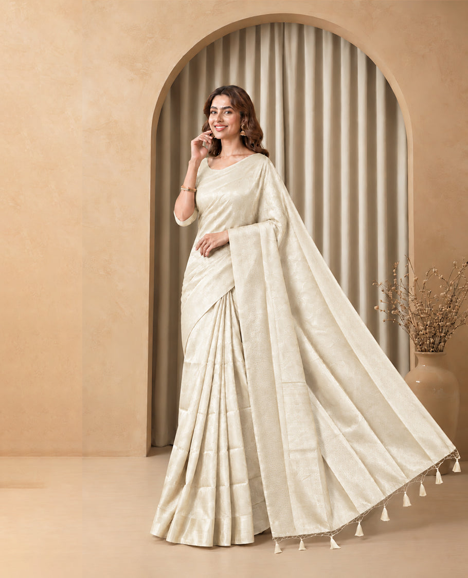 Off White Colour Elite Soft Silk Saree with silver zari leaf motifs on the body, a self Banarasi silver zari border and brocade pallu, Paired with a blouse Piece featuring small silver zari buttas.