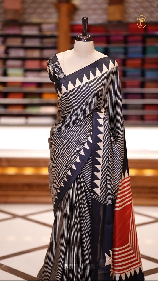 Black & Beige colour Turkey crepe saree featuring soft, flowy fabric with a rich texture, Designed with black and white stripes, bold triangular borders, and a red geometric pallu&  Comes with a matching blouse piece.