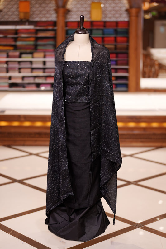 Black colour semi silk salwar material featuring subtle mirror work on the top, paired with a plain matching bottom & The set is completed with chiffon dupatta adorned with golden abstract prints for a classy finish.