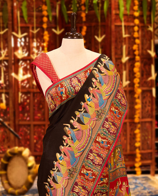 Black colour Pashmina silk saree exquisitely woven with vibrant mythological and architectural motifs across the body, bordered by elaborate narrative scenes and a grand artistic pallu, paired with a matching woven border blouse piece.