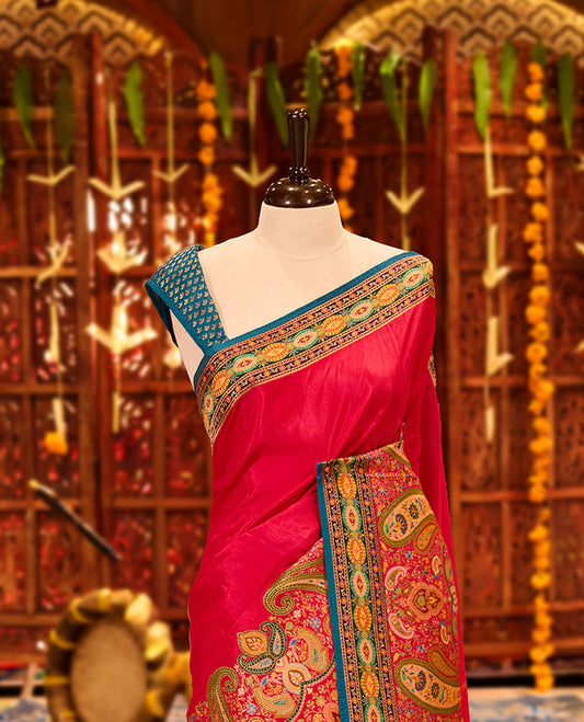Magenta colour Pashmina silk saree beautifully woven with intricate paisley and floral motifs in vibrant multicolour weaves, framed by teal and gold ornamental borders and an elaborate artistic pallu, paired with a coordinated woven blouse piece.