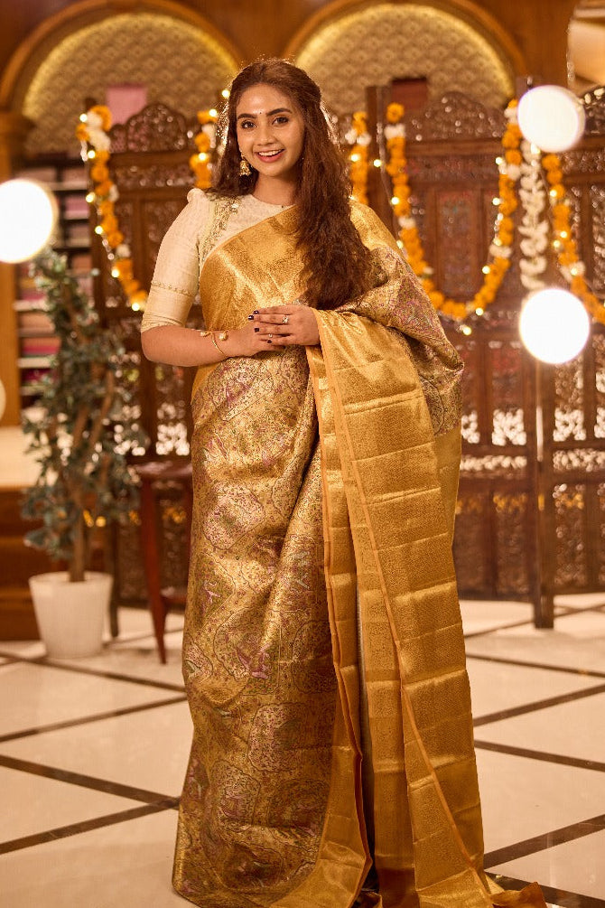 Gold colour Kancheepuram handloom tissue saree with Meena floral design, gold zari border and pallu, paired with matching blouse piece.