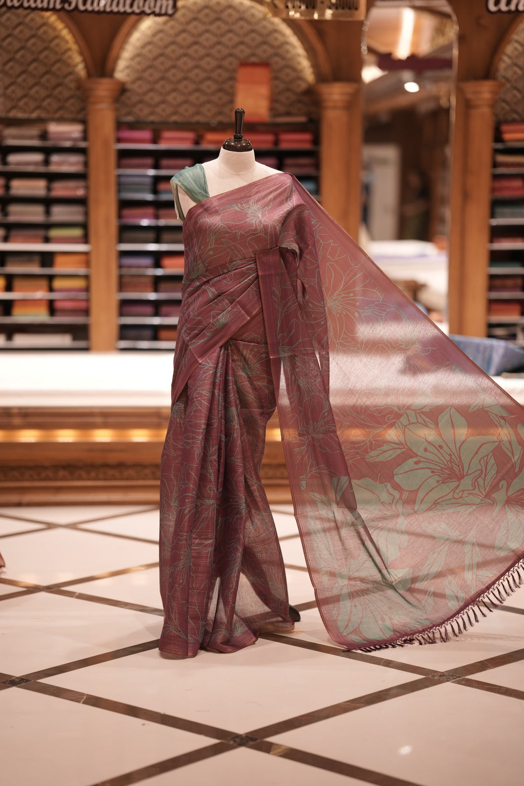 Wine & Teal green colour Semi linen tissue saree featuring full digital floral prints across the body, The saree is highlighted with a contrast floral printed pallu and comes with a plain contrasting blouse piece.