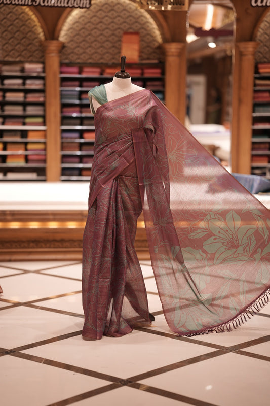 Wine & Teal green colour Semi linen tissue saree featuring full digital floral prints across the body, The saree is highlighted with a contrast floral printed pallu and comes with a plain contrasting blouse piece.
