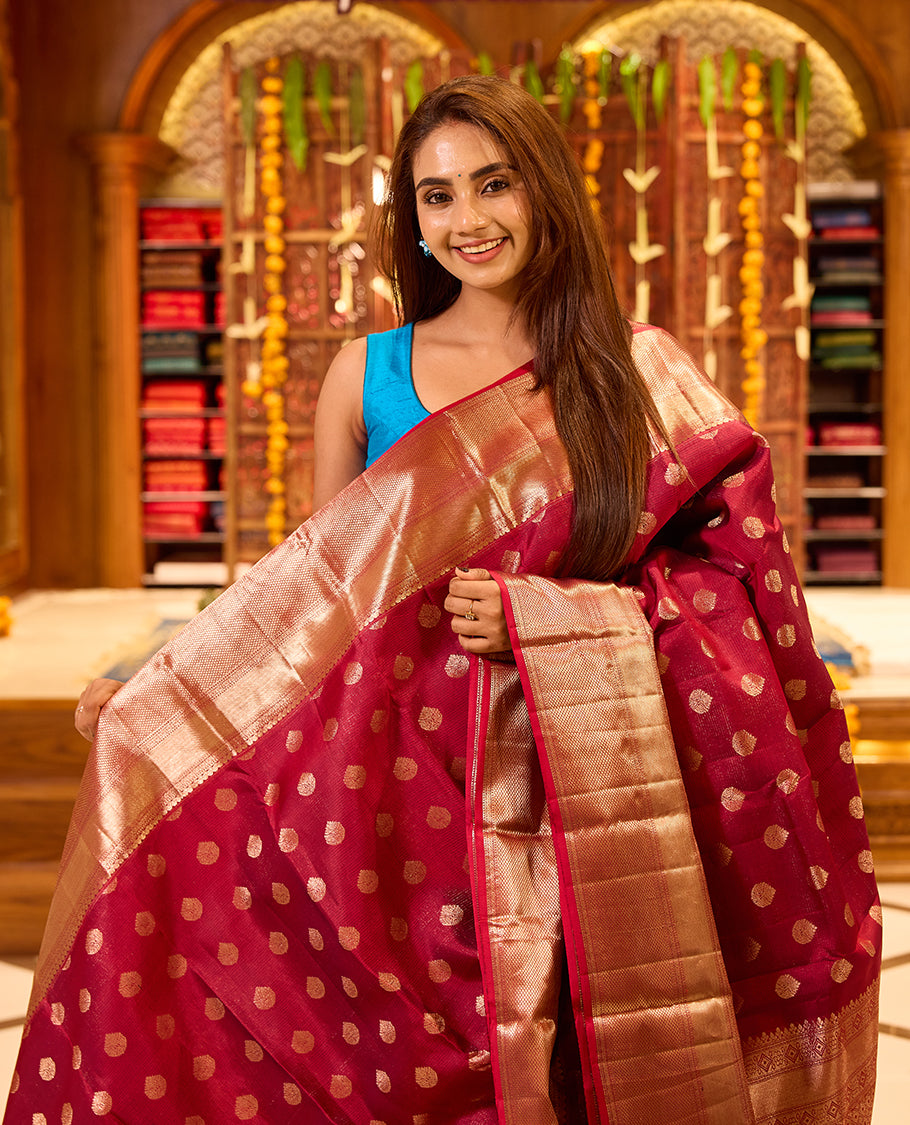 Wine colour Kancheepuram silk saree with classic gold zari polka motifs all over, complemented by a lustrous gold zari border and pallu, and paired with a matching blouse.